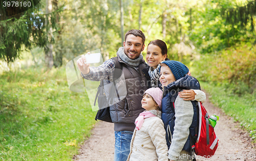 Image of family with backpacks taking selfie by smartphone