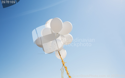 Image of close up of white helium balloons in blue sky