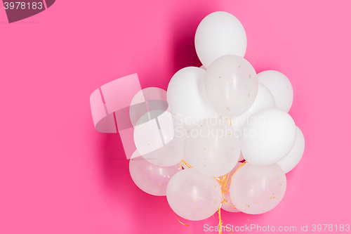 Image of close up of white helium balloons over pink