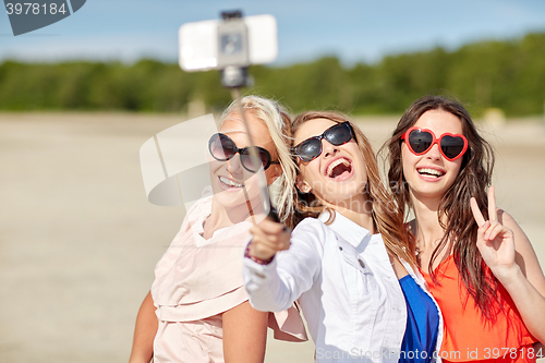 Image of group of smiling women taking selfie on beach