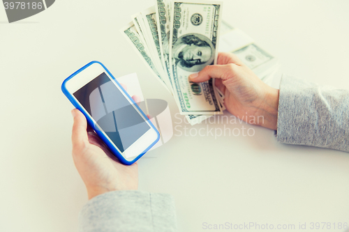 Image of close up of woman hands with smartphone and money