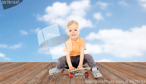 Image of happy little boy sitting on skateboard