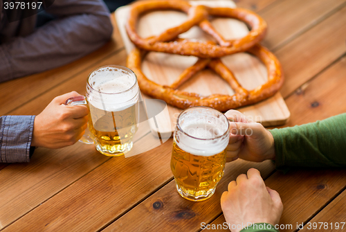 Image of close up of hands with beer mugs at bar or pub