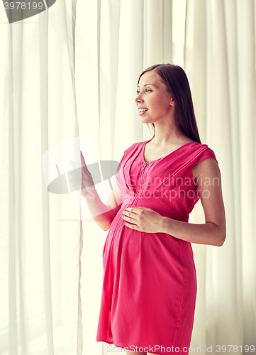 Image of happy pregnant woman with big tummy at home