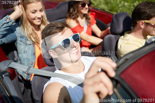 Image of happy friends driving in cabriolet car