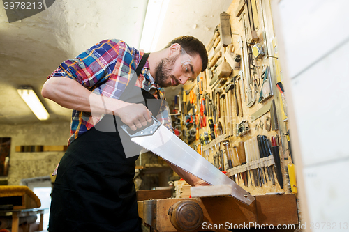 Image of carpenter working with saw and wood at workshop