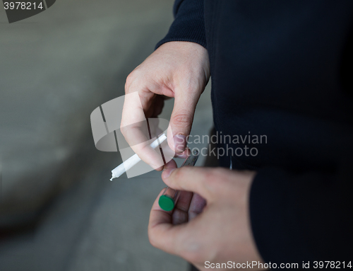 Image of close up of addict hands with marijuana joint tube