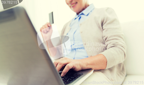 Image of senior woman with laptop and credit card at home