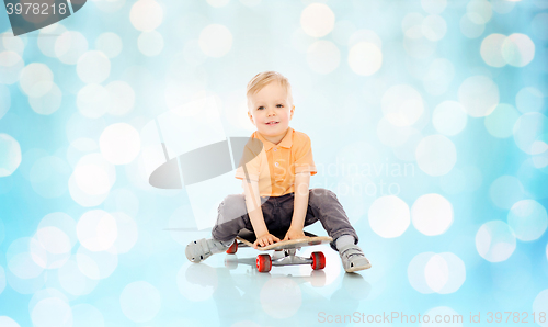 Image of happy little boy sitting on skateboard