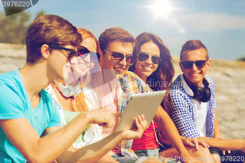 Image of group of smiling friends with tablet pc outdoors