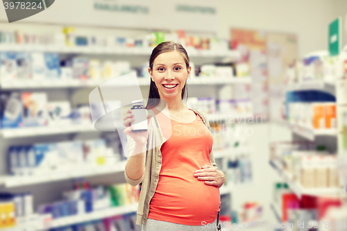 Image of happy pregnant woman with medication at pharmacy