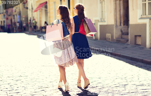 Image of happy women with shopping bags walking in city 