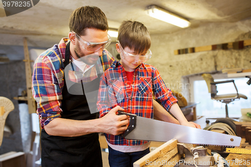 Image of father and son with saw working at workshop