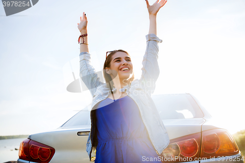 Image of happy teenage girl or young woman near car