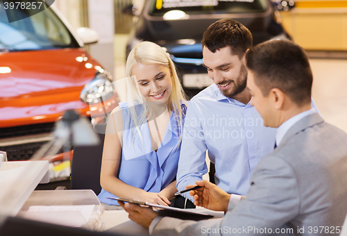 Image of happy couple with car dealer in auto show or salon