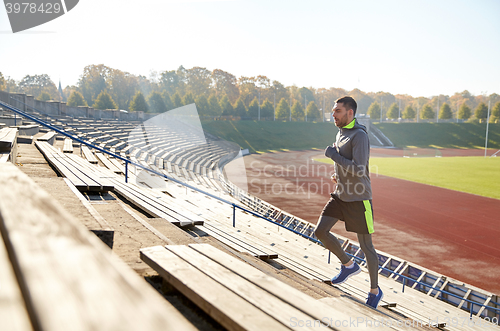 Image of happy young man running upstairs on stadium