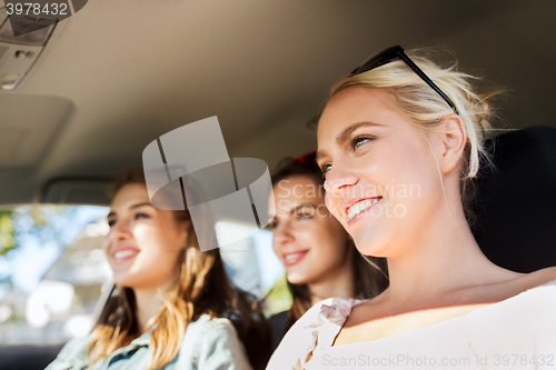Image of happy teenage girls or young women driving in car