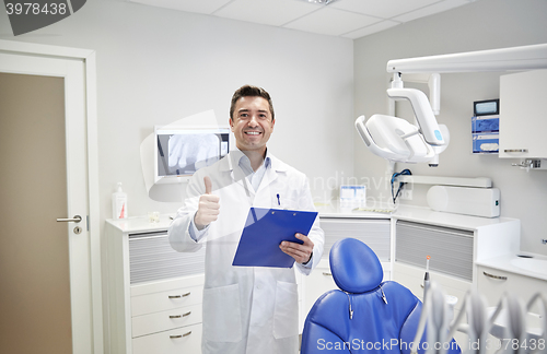 Image of happy male dentist showing thumbs up at clinic