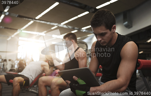 Image of group of men with tablet pc and dumbbells in gym