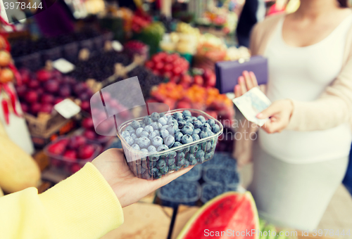 Image of pregnant woman with money buying berries at market