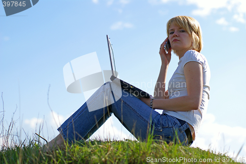Image of girl with notebook and phone on green grass