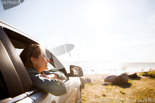 Image of happy teenage girl or young woman in car