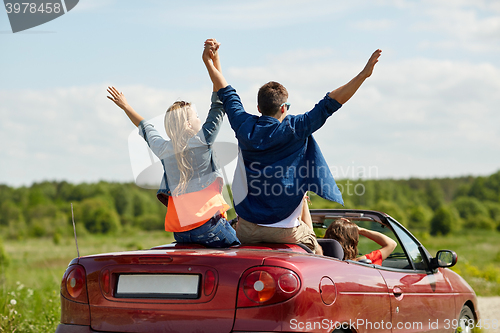 Image of happy friends driving in cabriolet car at country