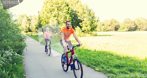 Image of happy couple riding bicycle outdoors