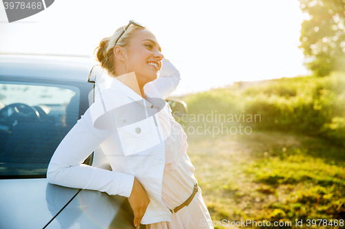 Image of happy teenage girl or young woman near car