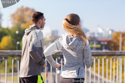 Image of happy couple running outdoors