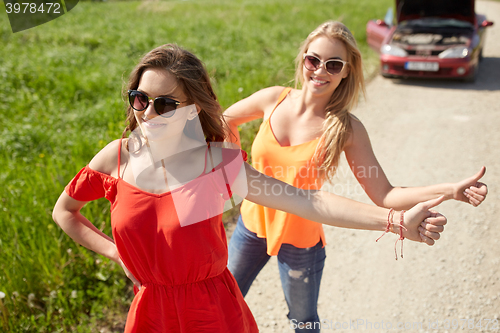 Image of women with broken car hitchhiking at countryside