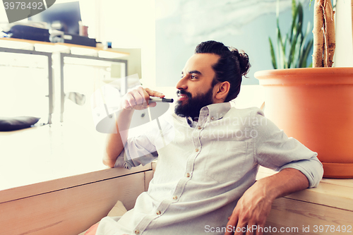 Image of smiling man with beard and hair bun at office