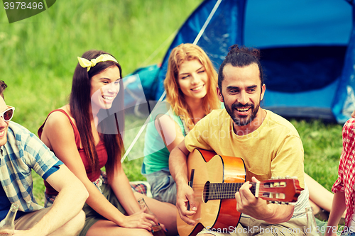 Image of happy friends with drinks and guitar at camping