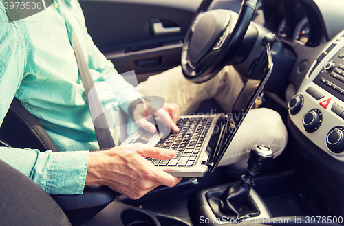 Image of close up of young man with laptop driving car