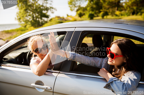 Image of happy teenage girls or women in car at seaside