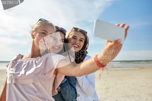 Image of group of smiling women taking selfie on beach