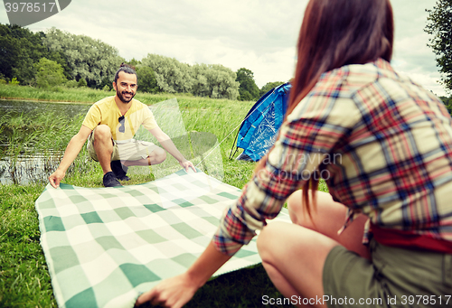 Image of happy couple laying picnic blanket at campsite