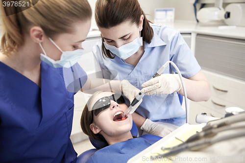 Image of female dentists treating patient girl teeth