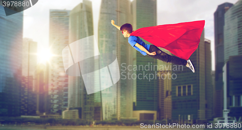 Image of boy in superhero cape and mask flying over city