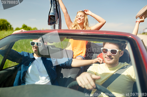 Image of happy friends driving in cabriolet car