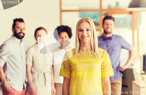 Image of happy young woman over creative team in office