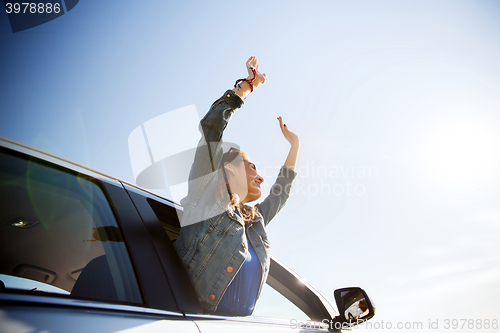 Image of happy teenage girl or young woman in car
