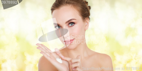 Image of happy young woman with moisturizing cream on hand