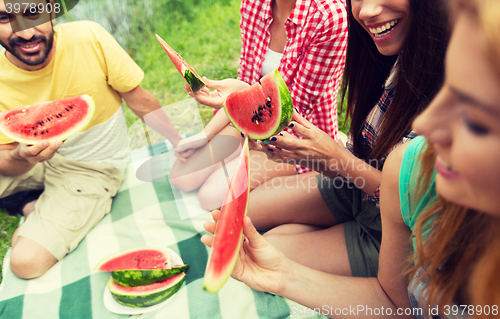 Image of happy friends eating watermelon at camping