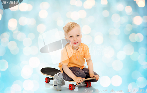 Image of happy little boy sitting on skateboard