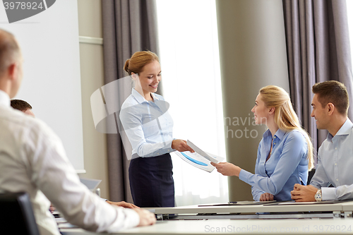 Image of woman giving papers to group of businessmen