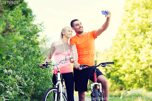 Image of couple with bicycle taking selfie by smartphone