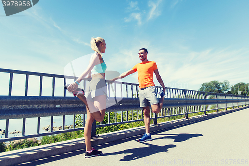 Image of smiling couple stretching outdoors