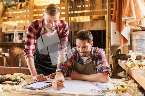 Image of workmen with tablet pc and blueprint at workshop