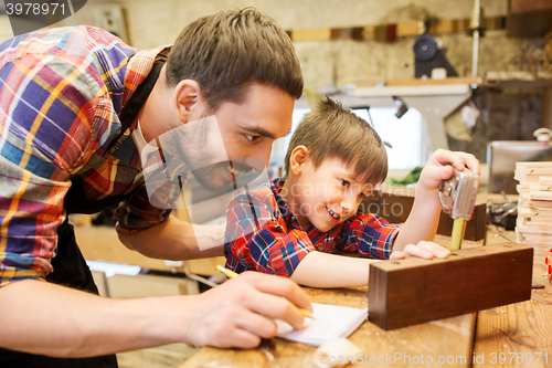Image of dad and son with ruler measuring plank at workshop